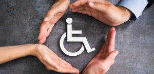 Hände beschützen einen Rollstuhl als Symbol für Behinderung