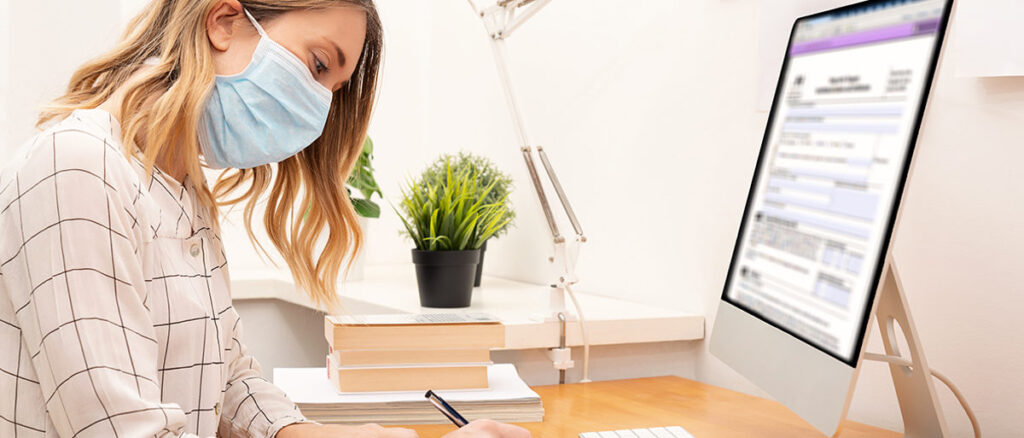 Frau mit Maske vor Computermonitor