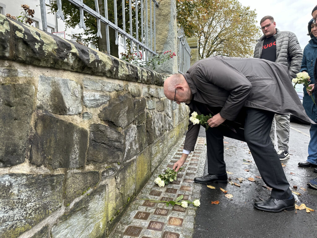 HWK-Präsident, Berthold Schröder, legt bei den Stolpersteinen in der Mozartstraße in Unna Blumen nieder.