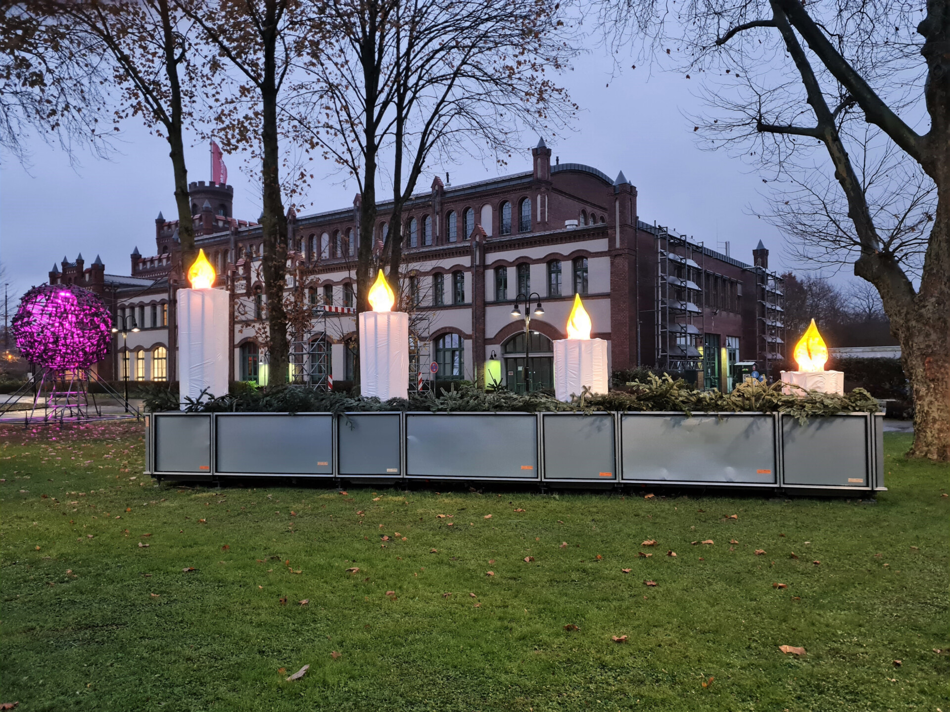 Am Bildungszentrum Hansemann in Dortmund-Mengede steht ein riesiges Adventsgesteck mit vier leuchtenden Kerzen. Eine spezielle und jährlich neu konstruierte Aktion des Gerüstbau-Handwerks zu Weihnachten.